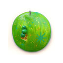 Flat backed sculpture of a green apple with small bite holes and a tiny green worm coming out of it.