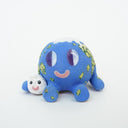 Ceramic sculpture of a blue planet with green floral dots, smiling and sitting next to a tiny moon.