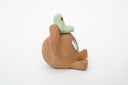 Sculpture of a brown, rounded character with legs sitting down. It holds a green smiling alien character atop its head.
