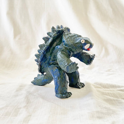 Stylistically messy sculpture of Gamera, a turtle monster with 2 large underbite fangs. It stands on 2 feet with its arms out in front of it. 