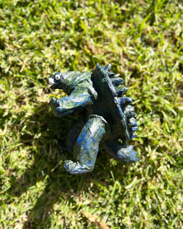Stylistically messy sculpture of Gamera, a turtle monster with 2 large underbite fangs. It stands on 2 feet with its arms out in front of it.