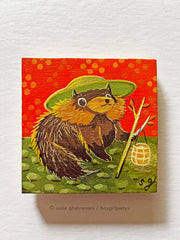 Painting of a chubby tanuki, a raccoon like creature, wearing a large brimmed green hat and holding a branch with a paper lantern on the end. It sits in a green stone path with a red background.