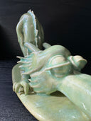 Jade colored ceramic sculpture of a dragon with a large front snout, positioned in the yoga stretch, child's pose.