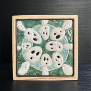 Ceramic tile, teal blue with a light blue circle, and 8 small white ghost like figures circling around the exterior, Kodama characters from Princess Mononoke.