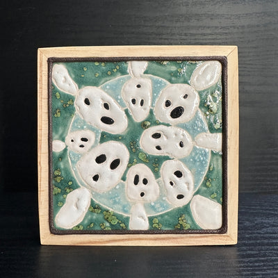 Ceramic tile, teal blue with a light blue circle, and 8 small white ghost like figures circling around the exterior, Kodama characters from Princess Mononoke.