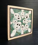 Ceramic tile, teal blue with a light blue circle, and 8 small white ghost like figures circling around the exterior, Kodama characters from Princess Mononoke.