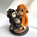 Two monkey figurines, one black and one orange, on a white background