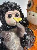 Two monkey figurines, one black and one orange, on a white background