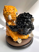 Two monkey figurines, one black and one orange, on a white background