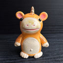 Ceramic figurine sculpture of an orange creature with mouse ears, a short but wide snout and a small horn coming out of the back of its head.