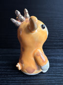 Ceramic figurine sculpture of an orange creature with mouse ears, a short but wide snout and 3 small horns coming out of the back of its head.