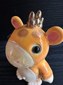 Ceramic figurine sculpture of an orange creature with mouse ears, a short but wide snout and 3 small horns coming out of the back of its head.