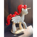 Ceramic unicorn figurine with red mane and tail on a wooden surface