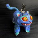 Colorful cat-like figurine with a small figure on its back against a dark background