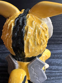 Ceramic figurine sculpture of a beige, yellow and black moth monster with round black eyes and small fangs.