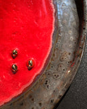 Red plate with gold studs on a textured metal surface