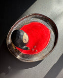 Ceramic plate with a small No Face figurine and air plant on a dark surface
