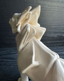Off white ceramic sculpture of a wolf seemingly made out of paper, folded like an origami sculpture. 