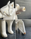 Off white ceramic sculpture of a wolf seemingly made out of paper, folded like an origami sculpture. 