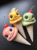 Three colorful ice cream cone toys with faces on a dark background