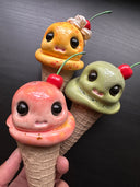 Three cartoonish ice cream cones with faces on a dark background