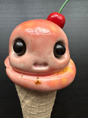 Ceramic figure of an ice cream cone with large cartoon style eyes and a cherry on top. 