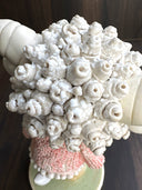 Ceramic figurine of a cute anthropomorphic sheep, with large shiny eyes and curled horns. She wears a pink textured sweater and tennis shoes.