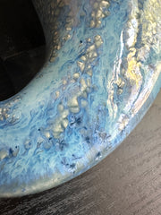 Close-up of a marbled ceramic glaze with blue and gold colors on a dark background