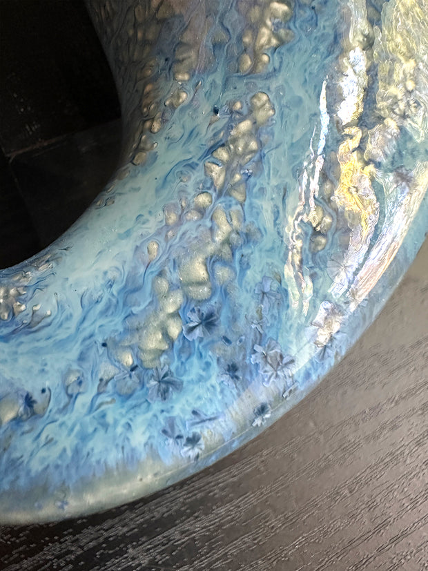 Close-up of a marbled ceramic glaze with blue and gold colors on a dark background