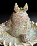 Ceramic sculpture of Totoro in a ceramic plate with cord tied around it.