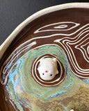 Ceramic dish with decorative elements on a dark surface