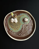Ceramic dish with decorative elements on a dark surface