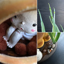 Ceramic sculpture of the Catbus from My Neighbor Totoro, with smaller proportions than usual to depict it as a kitten. Inside it is a small girl with a surprised expression. A small white chibi Totoro stands in front of the cat on a base with fake grass and small stones.