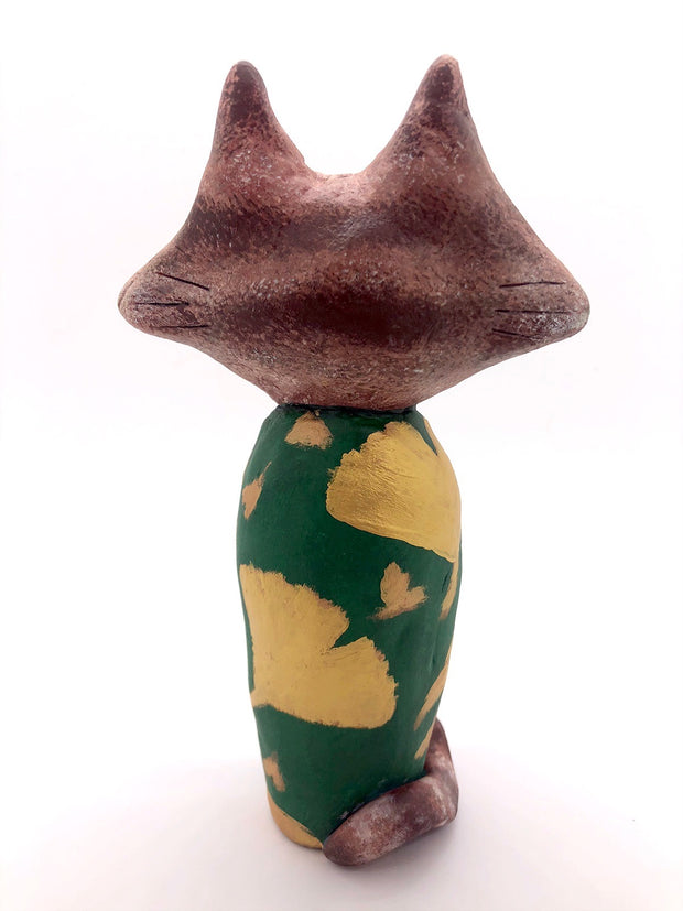 Sculpture of a large headed cartoon cat, wearing a green kimono with gold gingko leaves over it. Its eyes are closed and it has a content expression on its face.