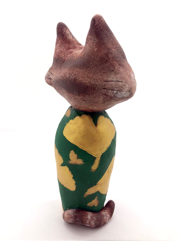 Sculpture of a large headed cartoon cat, wearing a green kimono with gold gingko leaves over it. Its eyes are closed and it has a content expression on its face.