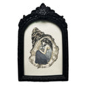A framed illustration of a woman hugging a pearl, resting inside of an oyster shell, set in an ornate black frame against a white background.