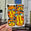 Paper with illustrations of 4 cartoon cat heads, stylized versions of Garfield held in someone's hand.