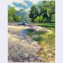 Watercolor landscape painting of a rocky riverbed with green trees, a distant bridge, and blue sky, shown centered on a light gray background.
