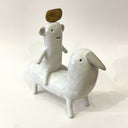 Ceramic sculpture of a bear like creature, white with smooth body, simplistic limbs and a piece of wood atop its head, riding on a bird like creature, standing on all fours with a large beak.