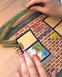 Assembly of a cut paper artwork of an urban brick building with a fire escape and graffiti on the wall.