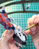 Detail of a person painting the sides of a cut paper artwork - a character dressed in traditional Japanese attire.