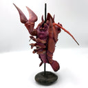 Sculpture of a lobster kaiju monster on a stand against a white background, as thought it is being barbecue skewer.