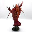 Sculpture of a lobster kaiju monster on a stand against a white background, as thought it is being barbecue skewer.