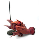 Sculpture of a lobster kaiju monster on a stand against a white background, as thought it is being barbecue skewer.