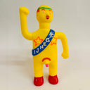 Yellow action figure with a blue sash and red shoes on a white background