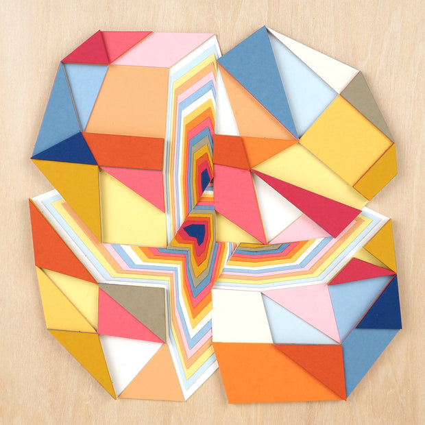 Geometric designed layered cut paper sculpture, creating a three dimensionality. A vertical and horizontal cross section of a 10 sided shape reveals many layers. Colors are earthy toned browns, oranges, yellows, blues and reds.