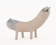 Ceramic sculpture of a long bodied, skinny character with small ears and eyes standing on 4 short legs.