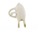 Ceramic sculpture of a light tan character with small ears, eyes and 4 legs. It has curved handle liked shapes overlapping on its back.