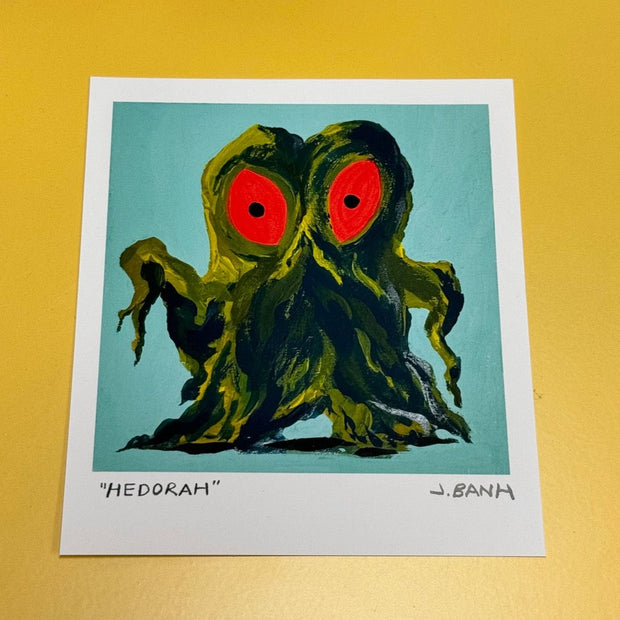 Art print of a painting of Hedorah, a dark green smog slime monster with large red eyes. It stands with its arms slightly extended. Print is signed and labeled.