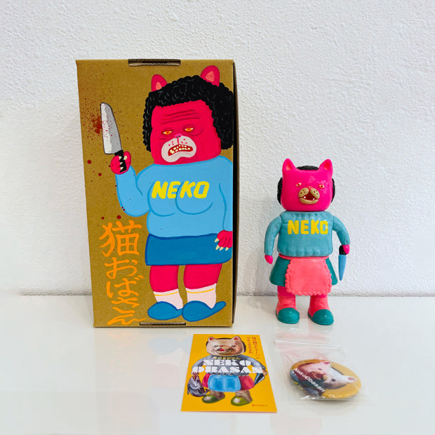 Neon pink painted soft vinyl figure of a cat headed humanoid with light pink hair, wearing a blue sweater that says "neko" and a blue skirt with a pink frilly apron. She holds a blue knife.